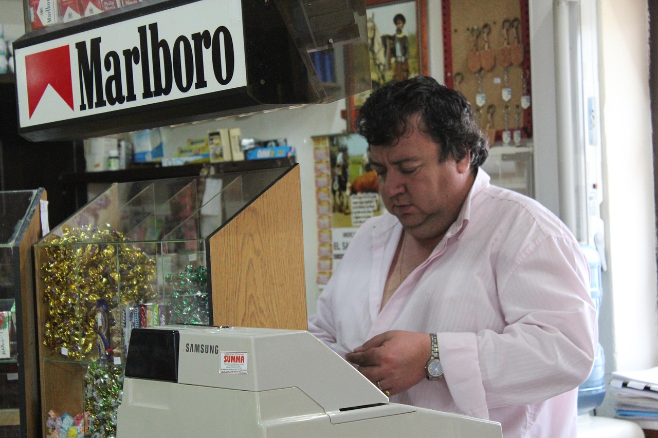 Un tabaccaio mostra un Gratta e Vinci vincente con un sorriso, circondato da biglietti e clienti curiosi.